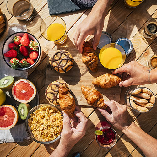 Vertical view of table full of breakfast food and group of peopl
